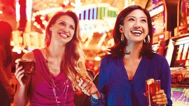 Two women with drinks at slot machines, featured on Ameristar Council Bluffs’ website.
