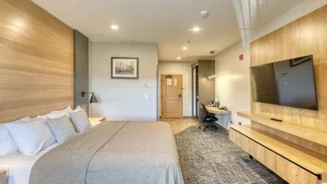 Guest room at The Lodge at Deadwood with a king-sized bed, wall-mounted television, and desk.